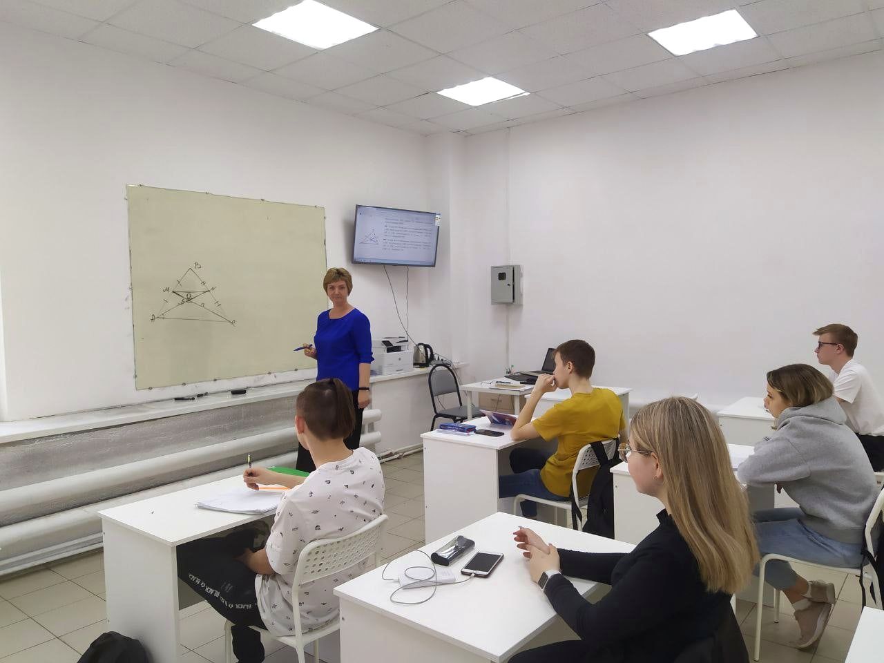 Преподаватель объясняет задачу у доски старшеклассникам